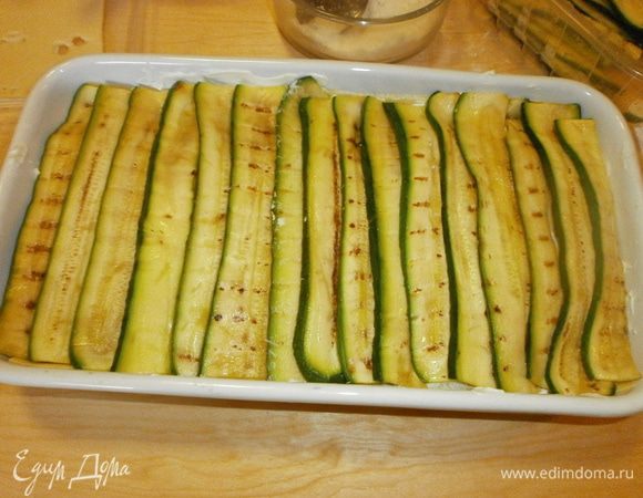 Выложить полосочки цуккини поперёк формы. Поперчить. В зависимости от колличества продуктов и размера формы, слои повторить. Может быть два или три. 
Верхний слой выкладываем цуккини.