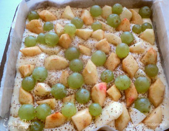 Форму (у меня 20х20см) застелить бумагой для выпечки, смазать маслом и вылить тесто.
Сверху выложить дольки яблок, вставляя их перпендикулярно в тесто, и виноград. Посыпать корицей.
