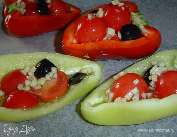 Перец выкладываем на противень, застеленный пергаментной бумагой и фаршируем его подготовленной овощной смесью. В каждую половинку перца добавляем по 1 десертной ложки оливкового масла.