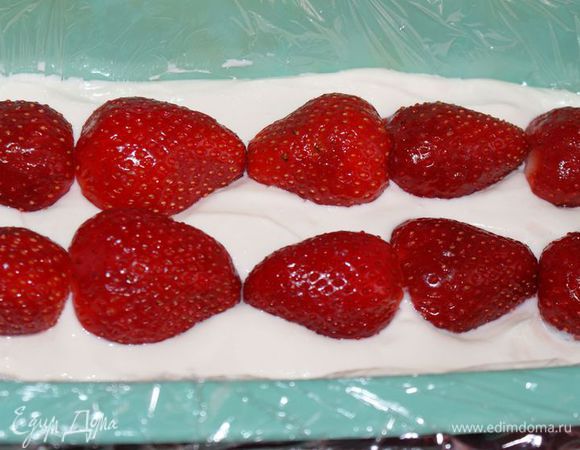 Форму для десерта выложить пищевой пленкой. Выложить половину творожной массы. Сверху выложить клубнику.