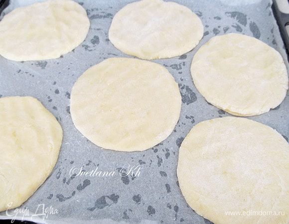 Стол подпыляем мукой, из теста формуем 6-7 шариков. Каждый из них обваливаем в муке и формуем лепешки. Я лепила и формировала ладошкой. Теперь переносим их на противень, выстланный пергаментной бумагой. 
