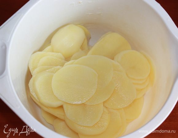 Картофель помыть, почистить, нарезать с помощью овощечистки тонкими кружочками. Здесь очень важно как можно тоньше нарезать картофель (овощечистка идеально справляется с этой задачей). Чем тоньше нарезаны картофельные пластинки, тем быстрее приготовится блюдо и тем более вкусным оно будет.