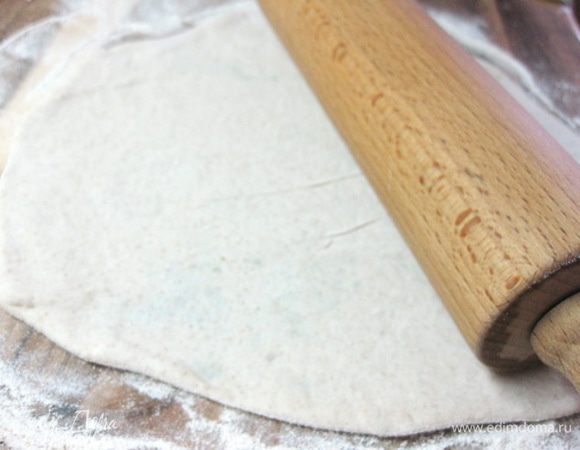 Немного придавить полученный шарик с начинкой рукой, чтобы получилась плоская лепешечка, обмакнуть в муке и раскатать в тонкую большую лепешку.