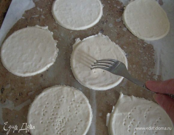 Выложить кружочки из теста на противень и наколоть вилкой.