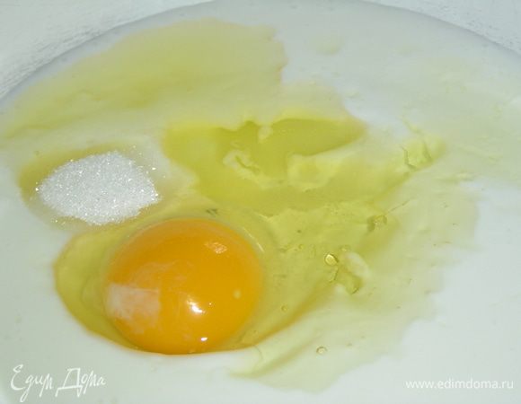 В кефир добавьте одно яйцо, сахар, соль и растительное масло, хорошо перемешайте.