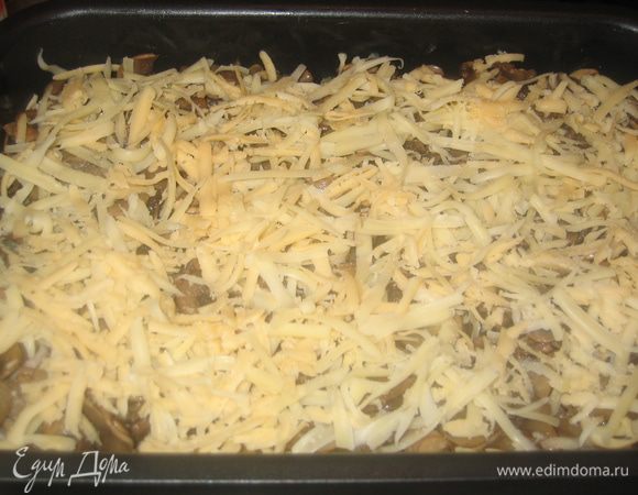 Сверху на мясо выложить поджаренные грибы...посыпать тертым сыром (1/2 часть).