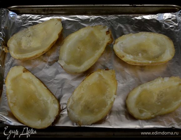 Пока картофель в духовке, прожарьте бекон до хруста, выложите на бумажное полотенце, как остынет - поломайте его на кусочки.
Когда картофель готов, ополовиньте его и у каждого картофеля снимите мякоть стол. ложкой вокруг, так чтоб мякоть была лишь у кожуры. Выложите картофель на противень.