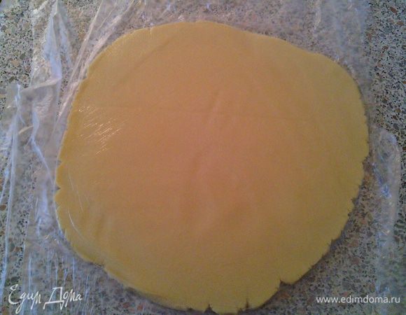 Выкладываем тесто на пищевую плёнку, прикрываем сверху ещё одним слоем плёнки и раскатываем пласт толщиной 0,7см. (без плёнки, тесто пристанет к скалке).
