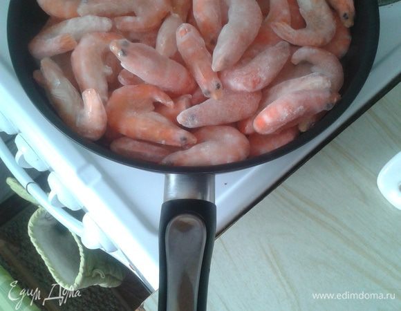 Креветки замороженные сложить в сковороду без масла и дать растаять льду. Воду слить, не дожидаясь когда сама выварится. Добавить оба масла и жарить до золотистого цвета 5-7 минут на сильном огне постоянно помешивая. 