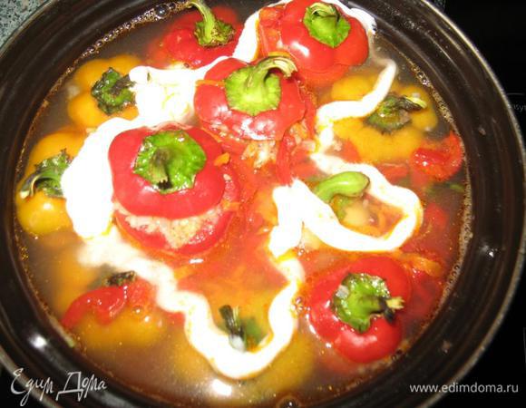 Фаршируем перцы, поплотнее, уминая начинку. Составляем перец в кастрюлю, так, чтобы при приготовлении он остался в вертикальном положении.Накрываем перцы крышечками, заливаем кипятком, добавляем остальные овощи( зажарку),сметану,ложку растительного масла.