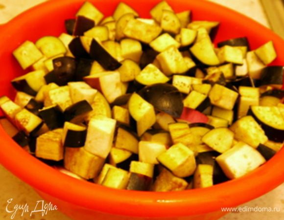 Нарезать баклажаны на мелкие кубики, сложить их в дуршлаг, посолить, поставить под вес и оставить на 30 минут. Через 30 минут баклажаны слегка отжать.
