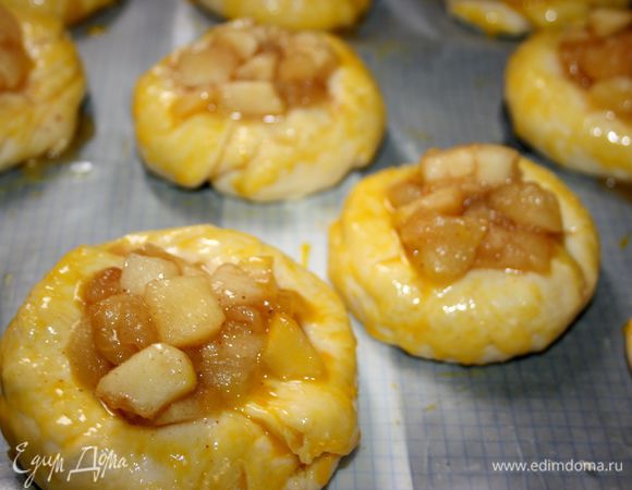 Тесто обмять и дать подняться еще раз.
Из теста сформировать плоские булочки, выложить их на смазанный маслом и простеленный пергаментом противень, на расстоянии 4 см друг от друга. Дать постоять 10 мин. В центре каждой булочки сделать углубление. Наполнить ватрушки яблочной начинкой и смазать края желтком.