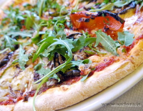 Муку насыпать горкой. Сделать углубление в центре и влить 60 мл тёплой воды. Добавить в воду дрожжи. Смешать их с водой (муку не подмешивать), накрыть крышкой и оставить на 10 минут.Через 10 минут открыть крышку, посолить муку (соль не должна попадать на воду с дрожжами) и начать замешивать тесто, добавив ещё 60 мл тёплой воды и 2 столовые ложки оливкового масла. Хорошо вымесить тесто. Оно должно выйти гладким и эластичным.
Обмазать тесто оливковым маслом, поместить в большую миску и поставить в тёплое место,накрыв влажным кухонным полотенцем, пока тесто не поднимется (около 2 часов). Тесто должно увеличить объём в два раза.
Осадить поднявшееся тесто руками и дать ему постоять ещё минут 30. Тесто готово для пиццы.
На присыпанной мукой поверхности или непосредственно в форме для пиццы, смазанной оливковым маслом, раскатать тесто. Если оно очень эластичное, не держит форму и сжимается после раскатывания, дать ему постоять несколько минут и снова раскатать.
Смазать поверхность пиццы томатным соусом «Наполетана».
Поместить пиццу в разогретую до 220° духовку на 10-15 минут.
Достать пиццу из духовки и разложить на поверхности ассорти из овощей, маслины и каперсы (количество по вкусу) и моцареллу, нарезанную кусочками.
Вернуть пиццу в духовку ещё минут на 10.
Готовую пиццу посыпать свежей рукколой и сразу подать на стол.

