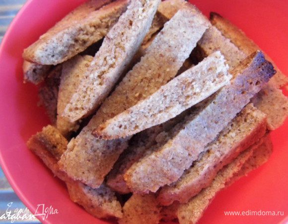 Отделить пекарскую бумагу от миндального коржа и порезать его на полоски шириной 1 см, которые разделить затем поперёк на сухарики длиной 5 см.