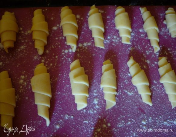 Закрутите от широкой к узкой части, должен получиться рогалик. Выложите на противень. У меня есть коврик для выпекания и я не смазываю его, чуть-чуть присыпаю мукой. Если у вас коврика нет, то просто смажьте противень маргарином. Выпекайте при 200°C 20–25 минут.