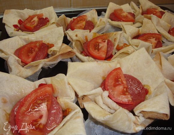 На дно корзиночек выкладываем по ложке фарша из овощей и мяска. Сверху ломтики колбасы и кружочки помидор.
