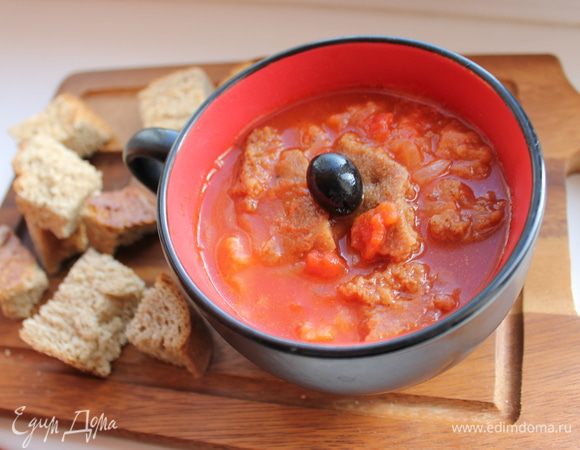 Добавить бульон с хлебом, уменьшить огонь и готовить ещё 10 минут, помешивая. Посолить, поперчить, добавить паприку, 2 столовые ложки оливкового масла. Через 5 минут суп готов.  Приготовить заправку для томатного супа: смешать мелко нарезанные маслины и растолченные в ступке с 1 зубчиком чеснока листья базилика. Разложить суп по тарелкам, положить по ложке заправки, посыпать тертым сыром. 