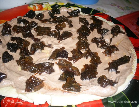 Начинаем сборку торта. На блюдо выкладываем первый корж, смазываем шоколадным кремом и выкладываем 1/4 часть чернослива.