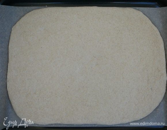 Разделить тесто на 2 части. Раскатать по ширине противня. Дно противня посыпать мукой или манкой. Выложить раскатанное тесто.