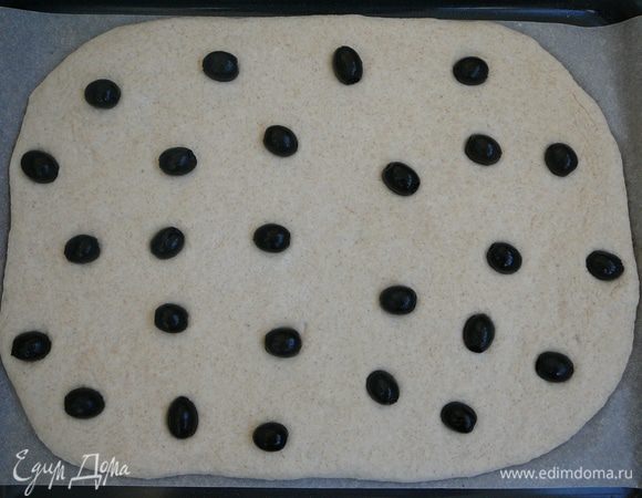 Равномерно распределить маслины, слегка притопив их в тесто.