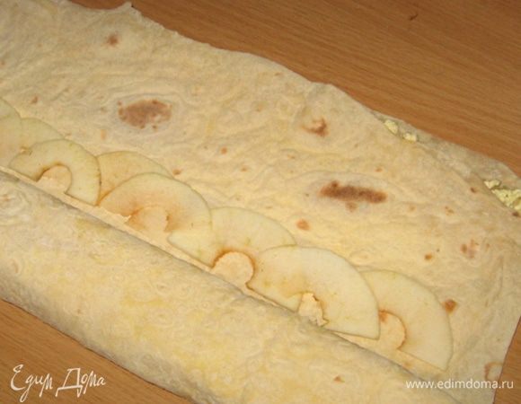 По длинному краю лаваша в ряд выложить яблоки. Подвернуть рулет один раз и к згибу (не под самый край) выложить второй ряд яблок. Завернуть рулет еще раз и выложить третий ряд. Затем закрутить рулет до конца. Рулет не должен быть плотным.