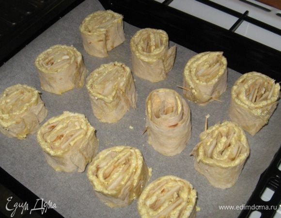 Теперь нарезаем рулет поперек острым ножом на дольки толщиной 3 или 5 см. Застилаем противень кулинарной бумагой (ничем ее не смазываем) и срезом вниз выкладываем завитки. Особо торчащий край можно приколоть зубочисткой, чтоб не очень-то раскручивался.