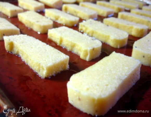 Противень застелить бумагой или силиконовым ковриком, смазать оливковым маслом.
Выложить брусочки поленты на противень и запечь в духовке под грилем (с приоткрытой дверцей) до легкой румяности (у меня это заняло 15 минут, но, как известно, у всех духовки разные, так что не отходите от нее далеко).