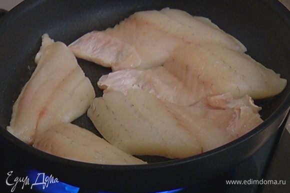 Разогреть в сковороде со съемной ручкой растительное масло и обжарить рыбу с одной стороны. Когда верхняя сторона рыбы посветлеет, отправить сковороду в разогретую духовку на 7–8 минут.