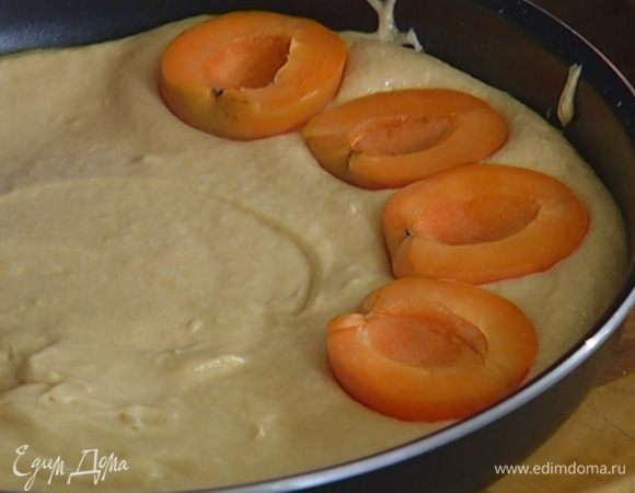 Выложить тесто в большую форму для выпечки, разровнять и разложить по всей поверхности абрикосы срезами вверх, слегка утопив их в тесте.