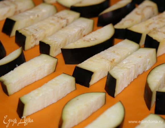 Баклажаны вымыть и нарезать на полоски толщиной 1,5 см. Разложить на противень застеленный силиконовым ковриком или пергаментной бумагой. Сверху смазать баклажаны растительным маслом. 