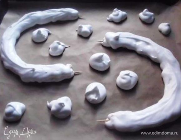 Два противня выстелить пекарской бумагой. На первый выложить миндальную массу, сформировав основу овальной формы.  Остальную  часть безе (без орехов) поместить в кондитерский мешочек  и выдавить на другой противень две дуги для ручек и несколько маленьких безешек для украшения. Я использовала зубочистки для укрепления конструкции, но если сделать ручки поменьше, можно обойтись и без них.
 