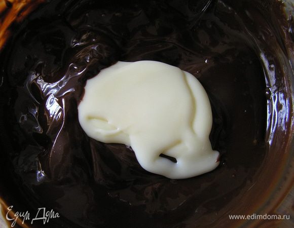 Приготовить шоколадно-хрустящую основу. Для этого растопить шоколад со сливочным маслом в микроволновке или на водяной бане, перемешать, добавить сгущеное молоко и сливки, перемешать.