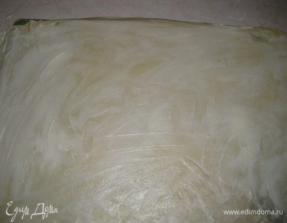 Намазываем тесто размягченным маргарином, удобнее всего это делать руками.