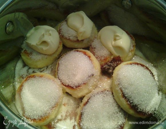 По мере приготовления, сразу укладываем готовые сырнички в кастрюлю. На каждый насыпаем 1 ч.л. сахара и выкладываем 1ч.л. (с горкой) домашней сметаны.