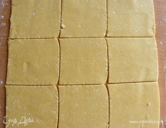 Тесто раскатать на присыпанной мукой поверхности. Нарезать на квадратики.