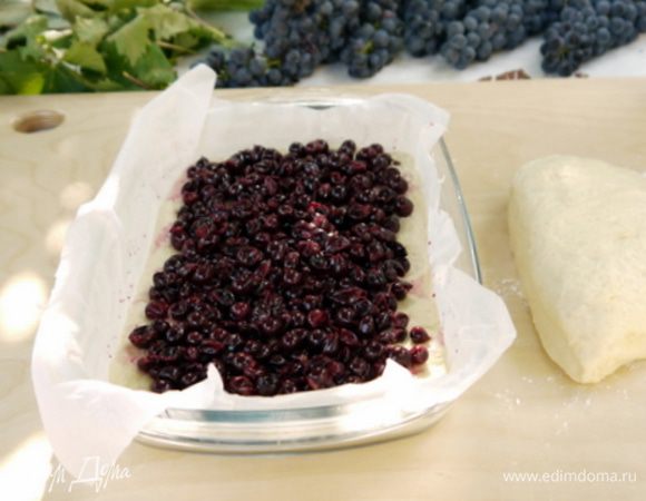 Перенести первый пласт в форму величиной примерно 22х28 см.
Распределить по тесту половину винограда.