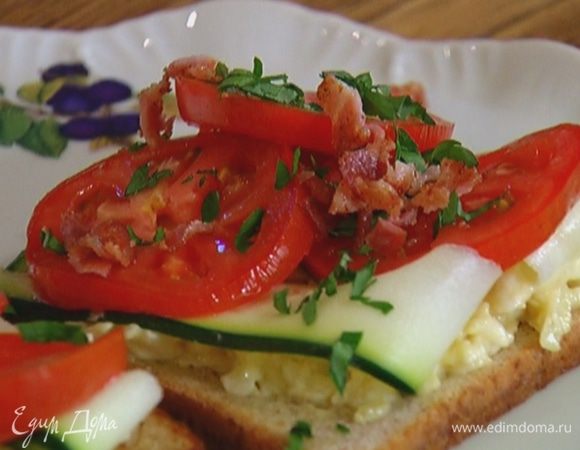 Поджаренный хлеб смазать сырной начинкой, выложить по 2–3 полоски цукини, затем помидоры и бекон, сверху присыпать петрушкой.