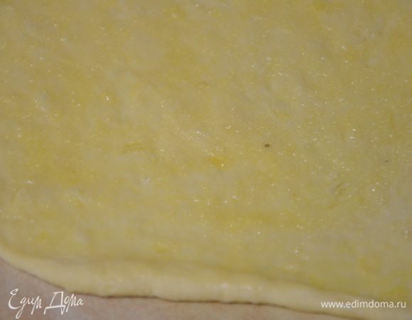 Разделить на две части(так удобнее),раскатать одну часть в прямоугольник.Смазать при помощи кисточки,растопленным сливочным маслом,присыпать поверхность сахаром.