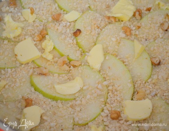 Выложить поверх яблок кусочки сливочного масла. Сверху посыпаем орешками, остатками сахара и корицы. 