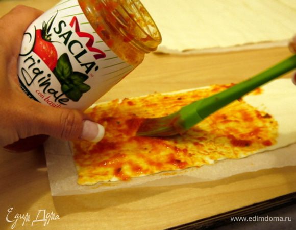 Смазать тесто с помощью кисточки соусом Saclà.
