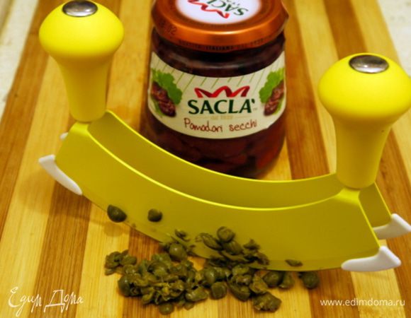 Смыть соль с каперсов под проточной водой. Промокнуть каперсы бумажным полотенцем и порубить.
Достать вяленые помидоры из баночки и дать стечь маслу. Порубить помидоры.
