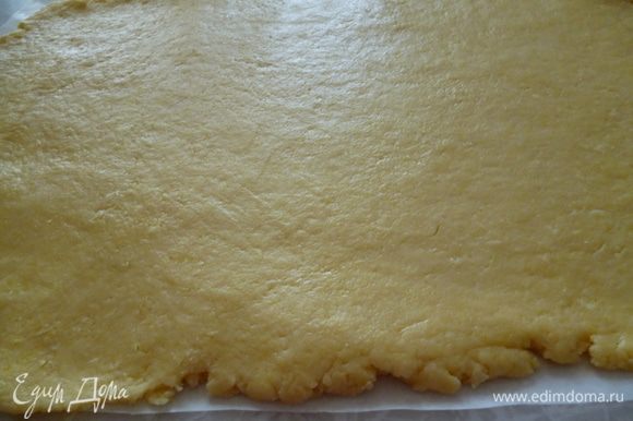 Достаем тесто из холодильника.Вырезаем кусок пергамента по величине вашей формы (включая и высоту бортика).Смазываем маргарином.Раскатываем тесто с помощью скалки на листе пергамента.