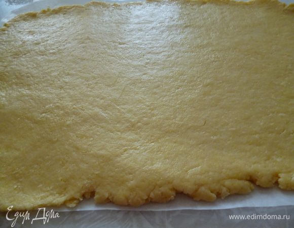 Достаем тесто из холодильника.Вырезаем кусок пергамента по величине вашей формы (включая и высоту бортика).Смазываем маргарином.Раскатываем тесто с помощью скалки на листе пергамента.