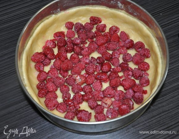 Форму смазать маслом. Выложить тесто и сформировать корж с бортами. Выложить на корж малиню ( вишню).