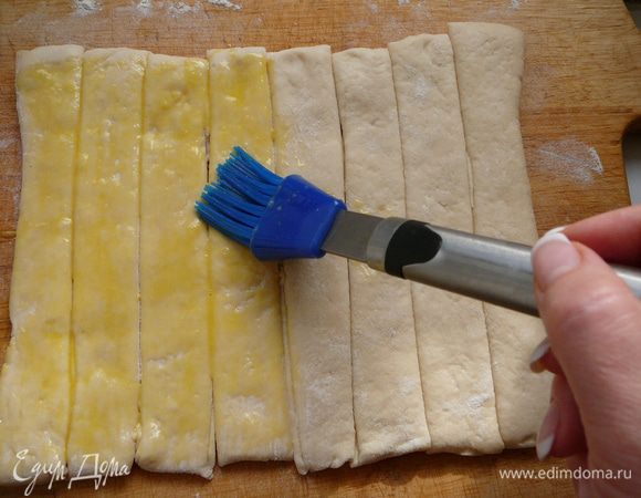 Яйцо слегка взбить и смазать им полоски из теста.