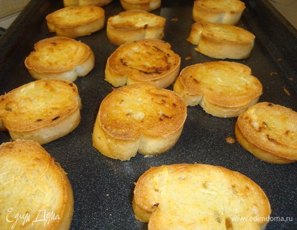 Чеснок мелко порубить или пропустить через пресс и смешать с оливковым маслом. Хлеб нарезать ломтиками, каждый смазать чесночным маслом и обжарить 10 минут  в духовке при температуре 200 градусов.