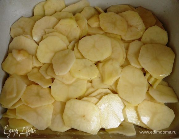 На дно формы налить немного масла и выложить ломтики картофеля.