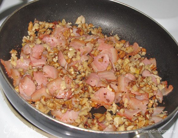 Тем временем нарезать бекон небольшимим кусочками и обжарить на оставшемся масле на среднем огне, 6-7 минут. Орехи порубить в крупную крошку, добавить к бекону и готовить еще 4 мин.