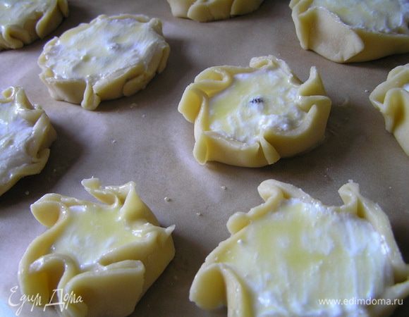 Ватрушки выложить на противень, застеленный бумагой для выпечки, смазать взбитым желтком 