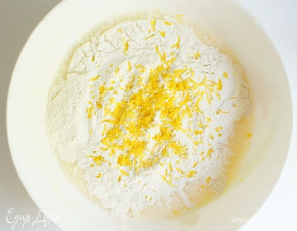 Постепенно добавить муку и цедру, продолжая взбивать, до тех пор пока тесто не станет густым и однородно-гладким.